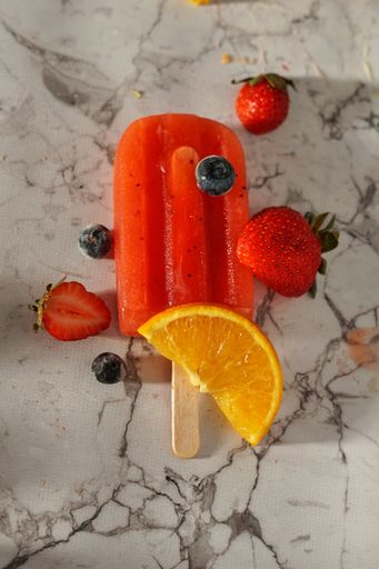 A top view of a strawberry ice cream with lemon slice and blueberries on a marble table