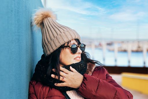 portrait of a woman with sunglasses and wool cap on a sunny autumn day walking in the city