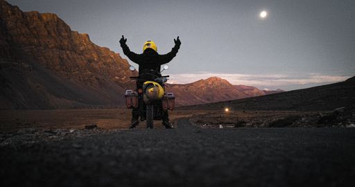A low angle shot of a motorcyclist celebrating victory in Spiti valley, India during twilight