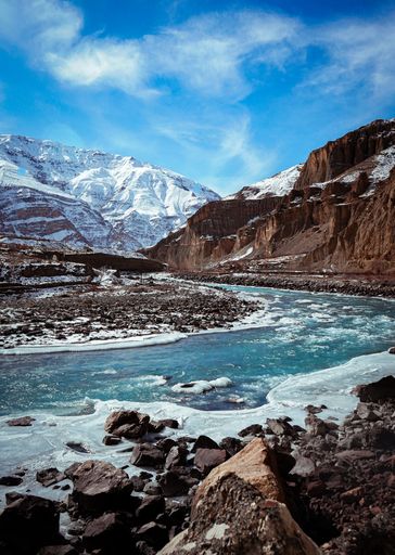 A vertical shot of Spiti valley in winter with frozen river and snow peak mountains