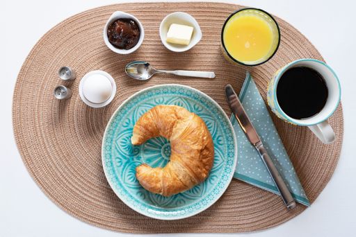 A top view of freshly-baked croissant on a porcelain plate with ingredients around it