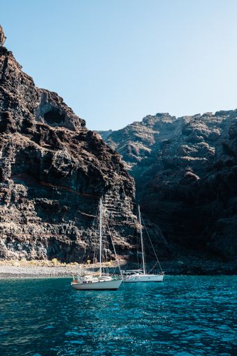 A vertical shot of boats sailing in a sea surrounded by cliffs