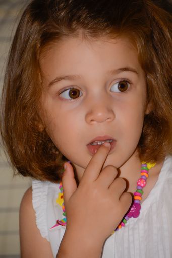 The picture shows a portrait of a girl with her finger on her lips with a thoughtful gesture.