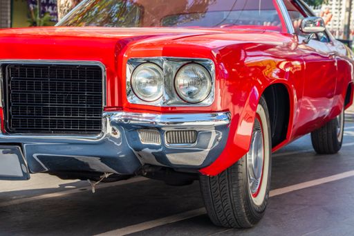 A red classic car or Muscle- Car is parked in front of a shop
