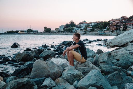 A young man on the rocky coast enjoying a beautiful sea view at sunset