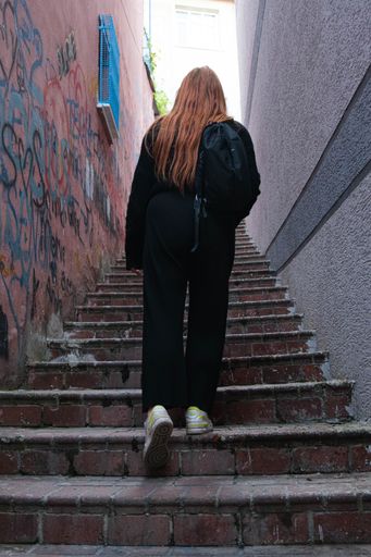 A vertical shot of a young woman walking up some stairs from the back