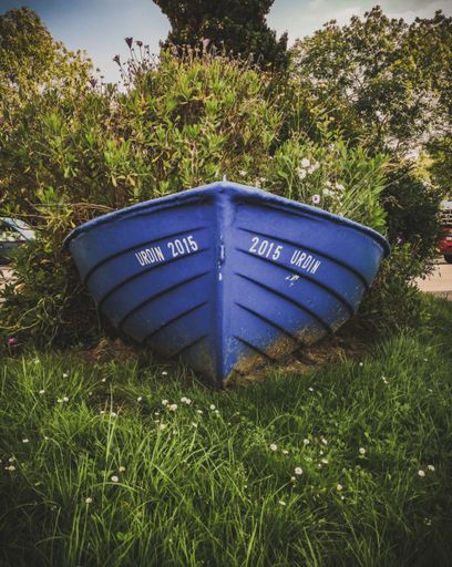 A closeup shot of a blue boat isolated on green grass