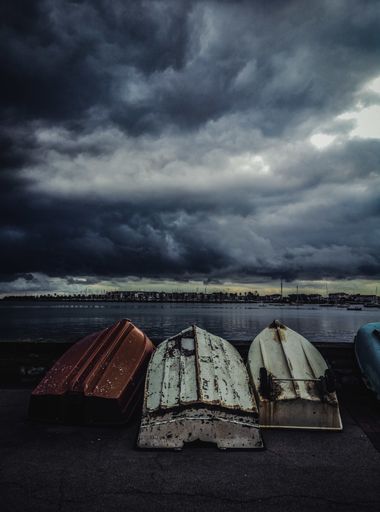 A vertical shot of old fishing boats turned upside down under the gloomy sky