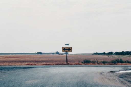 A wide shot of a road sign with a black arrow pointing both ways