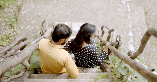 A young Indian couple having a rest on the treehouse steps during a date at a park