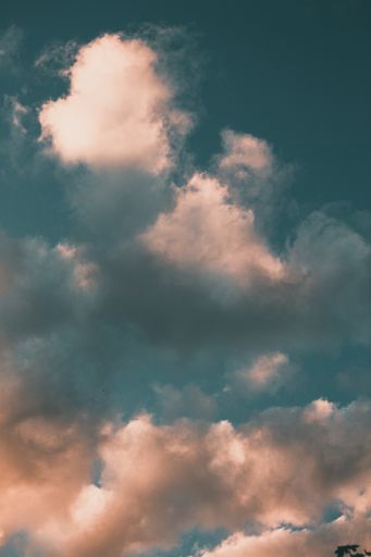 A vertical low angle shot of the magnificent fluffy clouds in the blue sky