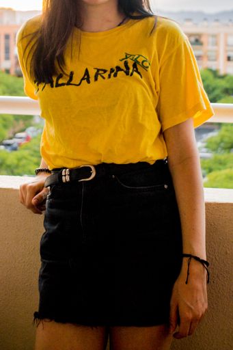 A vertical shot of a model wearing a yellow shirt and a black skirt