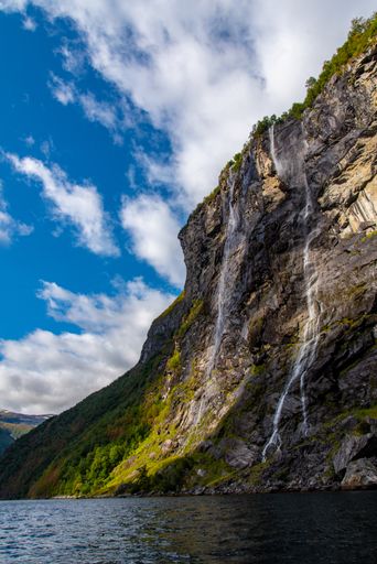 A vertical shot of a rocky cliff near a flowing river