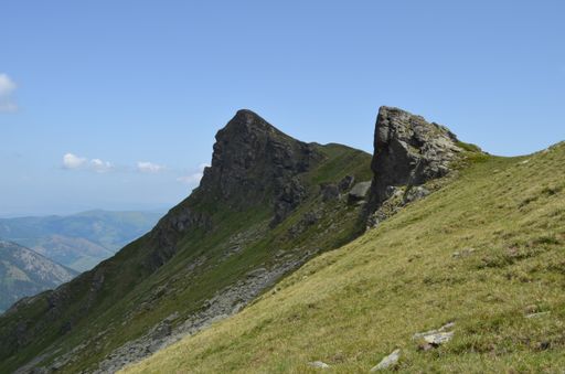 A view of the green rocky mountain peaks under the clear blue sky