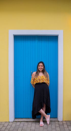 young latin woman model looking at camera in a blue door and yellow background