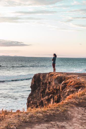 Man on the edge of a cliff watching the sunset