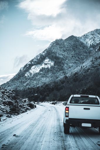 A vertical shot of snowy mountains in front of the road