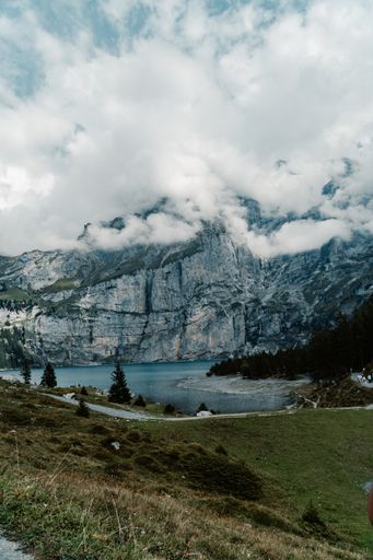 A vertical shot of the Oeschinensee near the rocks under the puffy clouds