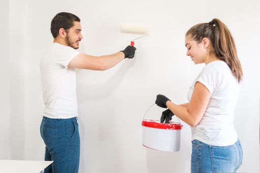 A young Caucasian couple painting walls in their new house