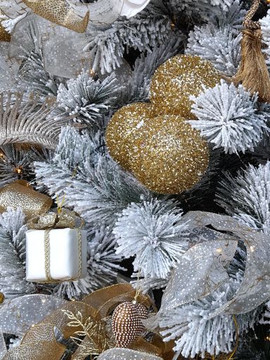 A vertical shot of a white Christmas tree with silver and golden color decoration on it
