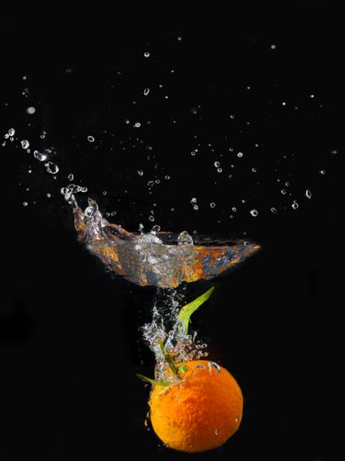 A vertical shot of tangerine submerged in water isolated on black background