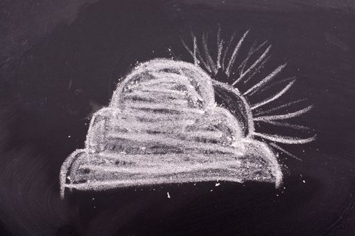 A closeup shot of the sun behind a cloud drawn with chalk on a blackboard