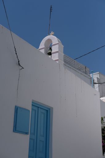 A vertical shot of a church with a blue wooden door on the white wall