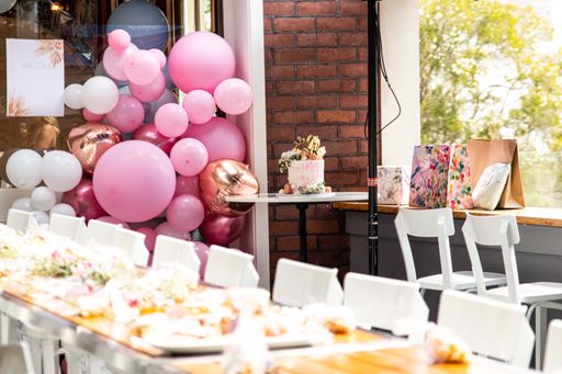 A birthday party decorated room, a cake, and pink balloons