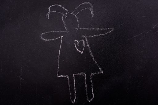 A closeup shot of a girl silhouette with a heard drawn with a chalk on a blackboard