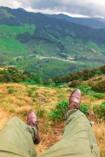 A hiker's feet hanging on air with a mountain view on the background