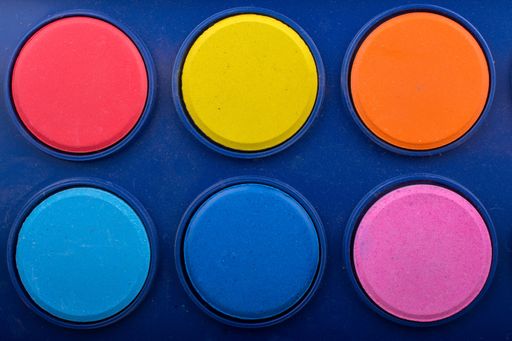 A closeup shot of red, yellow, blue, pink, red, and orange colors on a watercolor set
