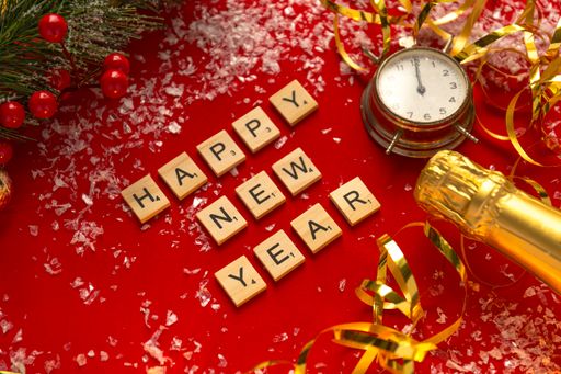 A red Christmas theme background with lettered wooden tiles forming the words Happy New Year