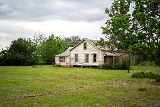 A large format shot of an abandoned white house in the green field