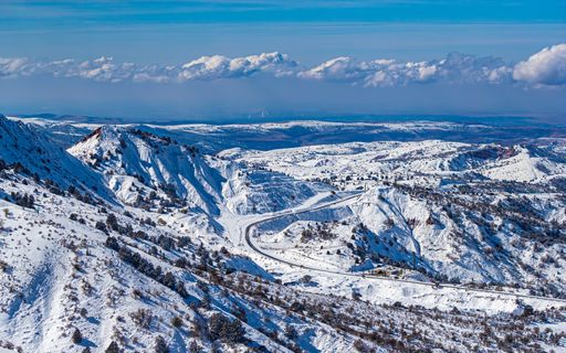 An aerial view of snowy mountains with a road through houses