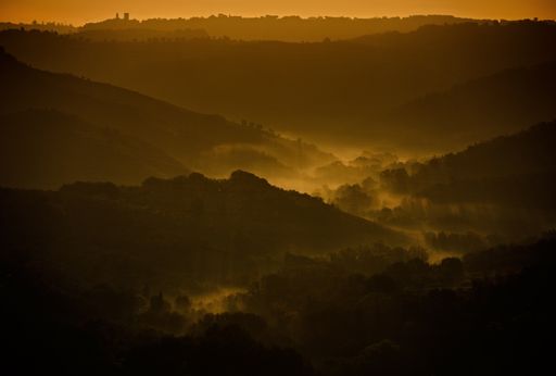 A landscape of hill silhouettes during a breathtaking sunset in the evening in Tuscany, Italy