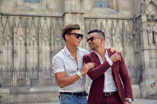 Two young males in formal clothes hugging each other and walking on a street