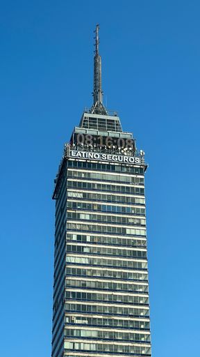 A vertical shot of the Latin American tower with a clock and a sign "LATINO SEGUROS" in Mexico