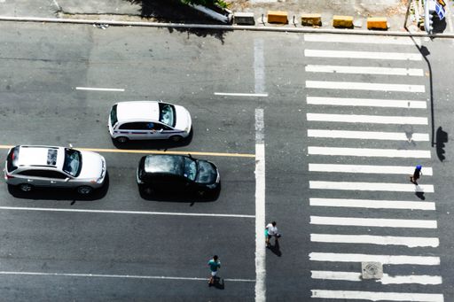 Three stopped cars and one person crossing the crosswalk.