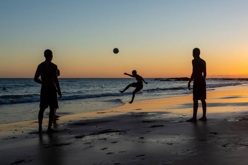 Young people playing sand football at sunset on Ondina beach in Salvador, Bahia, Brazil.