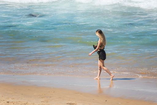 A female walking on the sands of Farol da Barra beach in Salvador, Bahia, Brazil