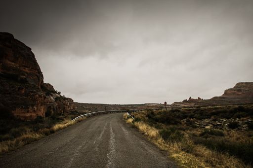A beautiful shot of an empty road in the middle of rocks and dry grass field under a cloudy sky