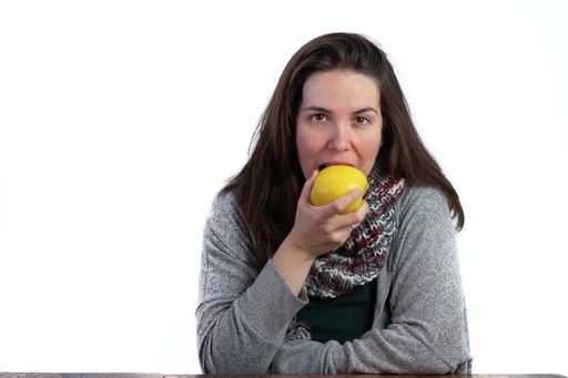 young brunette girl eating an apple on a white background with copy space