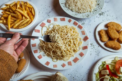 A man's hand with a fork taking spaghetti from the restaurant table