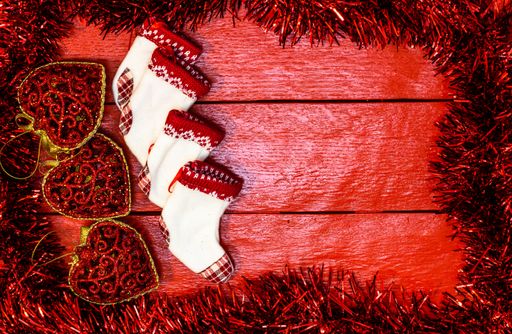 A Christmas garland around a red wooden board with decorations and copy space in the middle