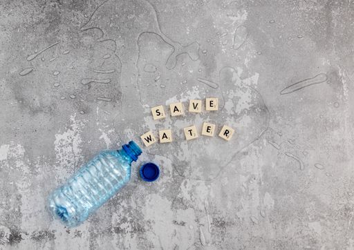 The water poured off a plastic bottle and the phrase "save water" made of scrabble blocks