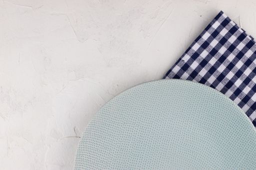 A blue and white checkered napkins with a blue plate on a white background with copy space