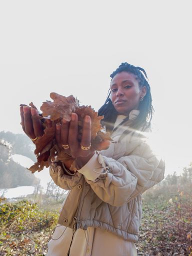 A vertical shot of a young African-American female holding leaves