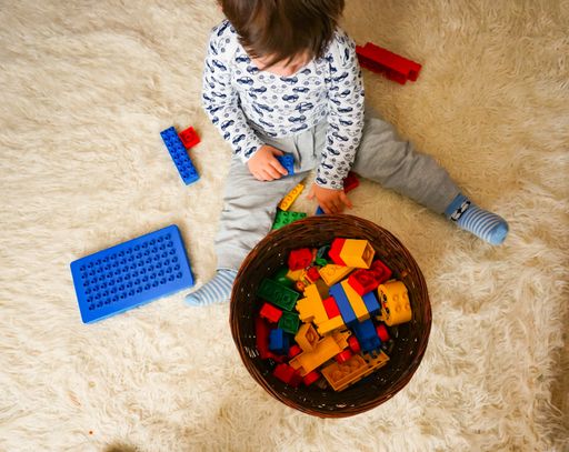 An overhead shot of a young boy playing with Lego Duplo bricks on a carpet. Swiecie, Poland