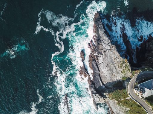 A breathtaking aerial shot of a sea wave crashing on rocky coast with spray and foam