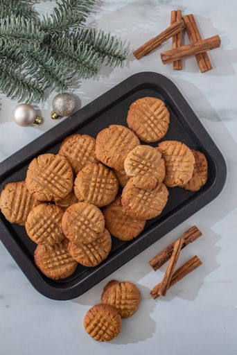A vertical shot of freshly baked peanut butter cookies on a tray with decorations on a table